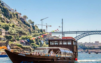 Boat cruising on the Douro River with Porto's Dom Luís I Bridge in the background.