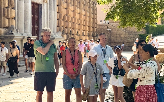 Tourists listening to a guide at the Alhambra, Granada, during a guided tour without Nasrid Palaces.