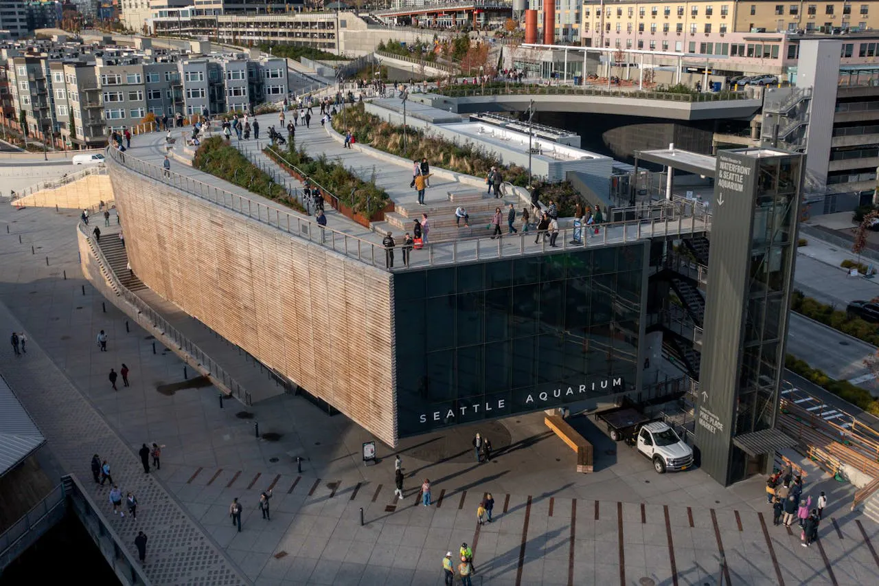 Seattle Aquarium entrance with visitors on the rooftop walkway and surrounding plaza.