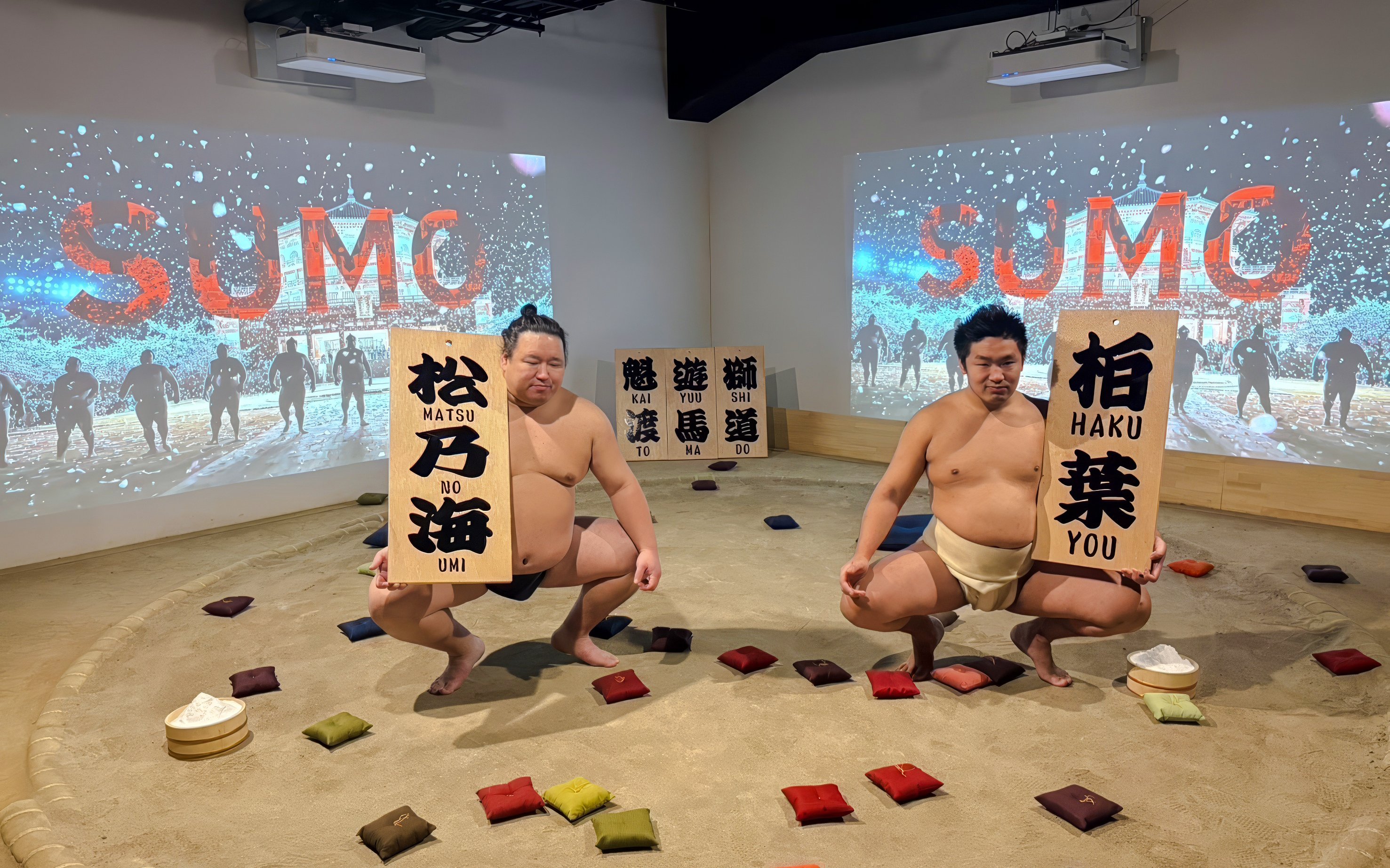 Sumo wrestlers performing at Ginza with souvenir signs in a sand ring.