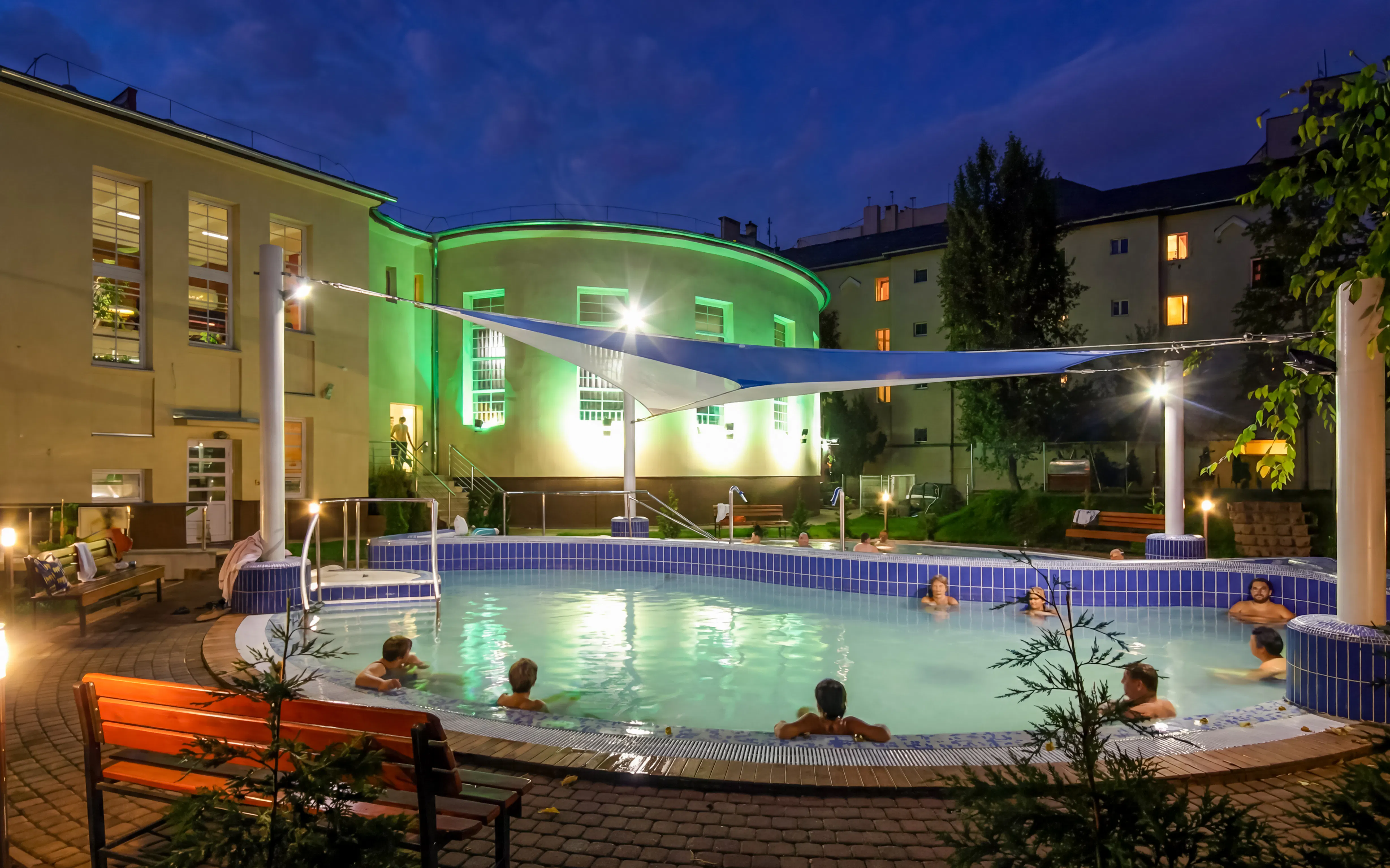 Outdoor thermal pool at Dandar Spa with people relaxing in the evening.