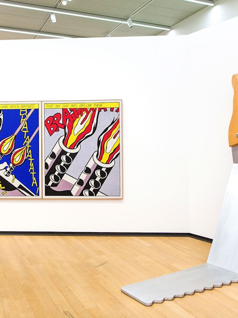 Visitor viewing pop art and large saw sculpture at Stedelijk Museum exhibits.