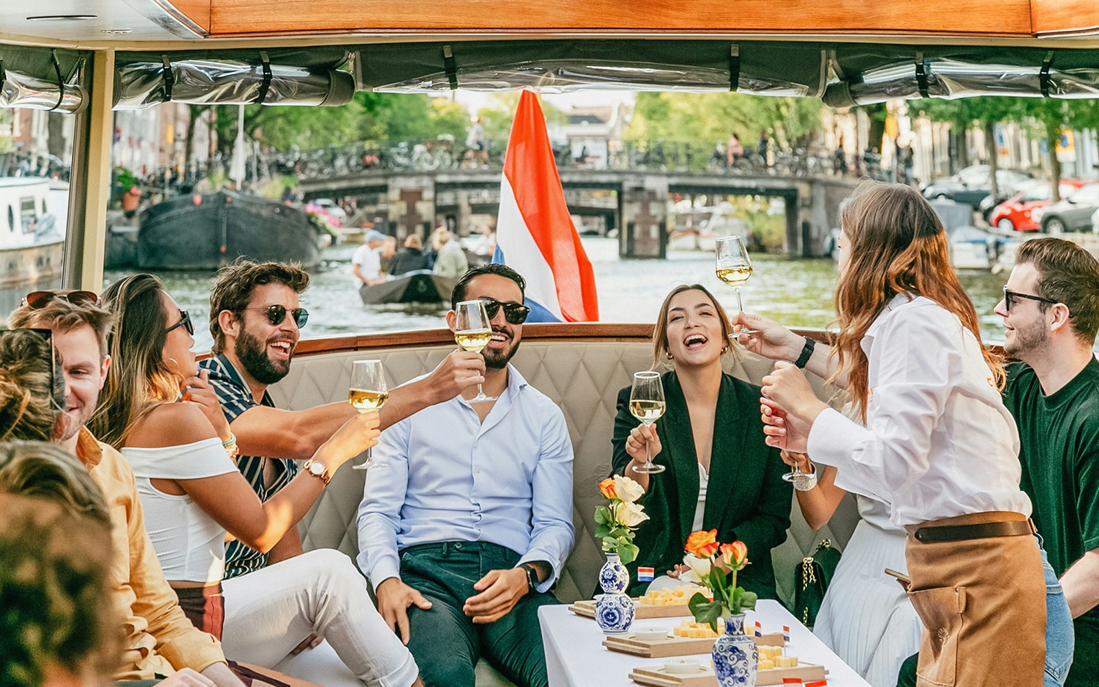 Amsterdam canal cruise with passengers enjoying cheese and drinks on an open boat.