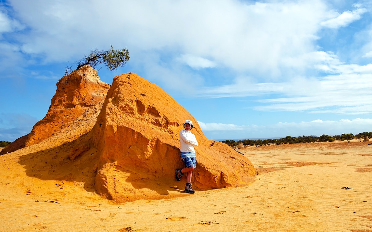 Person standing by a large limestone formation in the Pinnacles Desert, Western Australia.