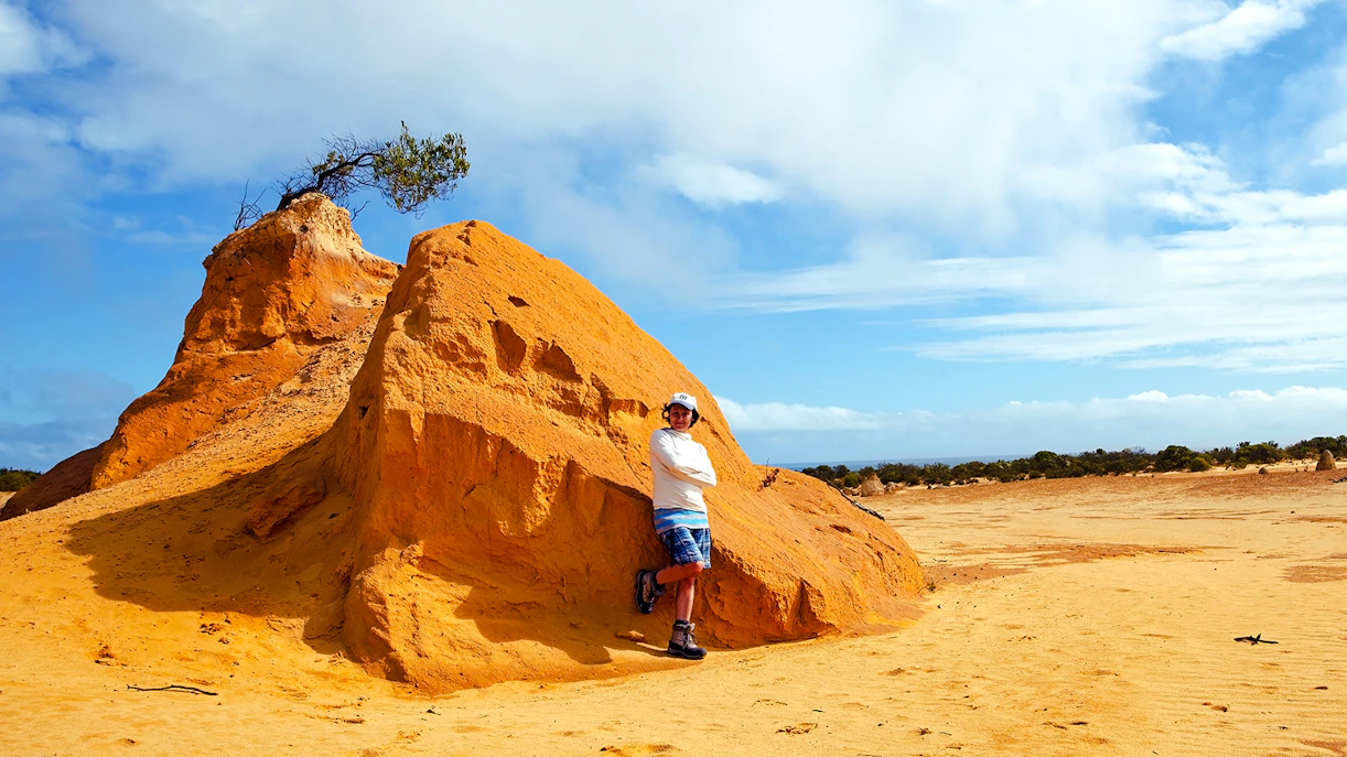Person standing by a large limestone formation in the Pinnacles Desert, Western Australia.
