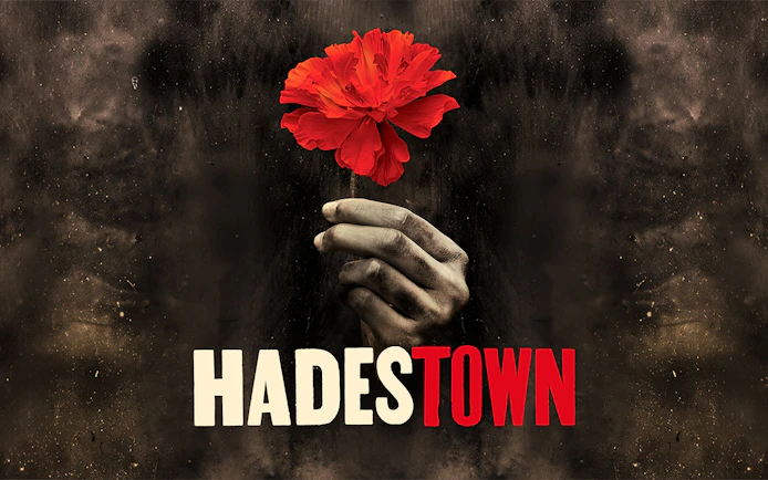 Hand holding a red flower with "Hadestown" text, West End production.