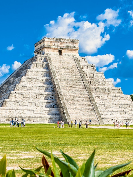 Chichen Itza pyramid with tourists exploring the site in Mexico.