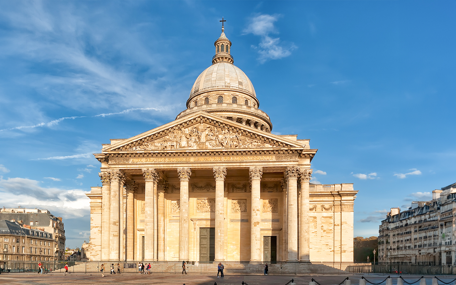Pantheon in Paris with neoclassical facade under blue sky.