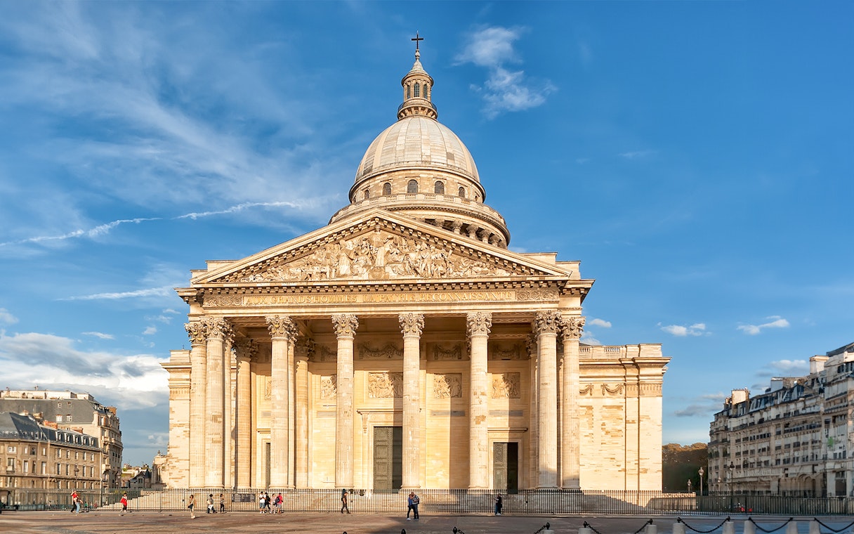 Pantheon in Paris with neoclassical facade under blue sky.