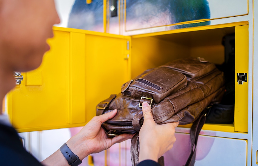 Man placing bag in locker at tourist attraction.