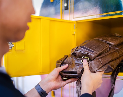 Man placing bag in locker at tourist attraction.
