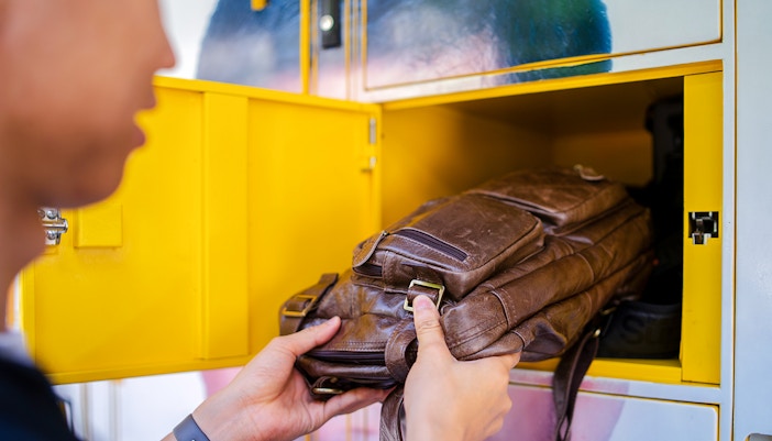 Man placing bag in locker at tourist attraction.