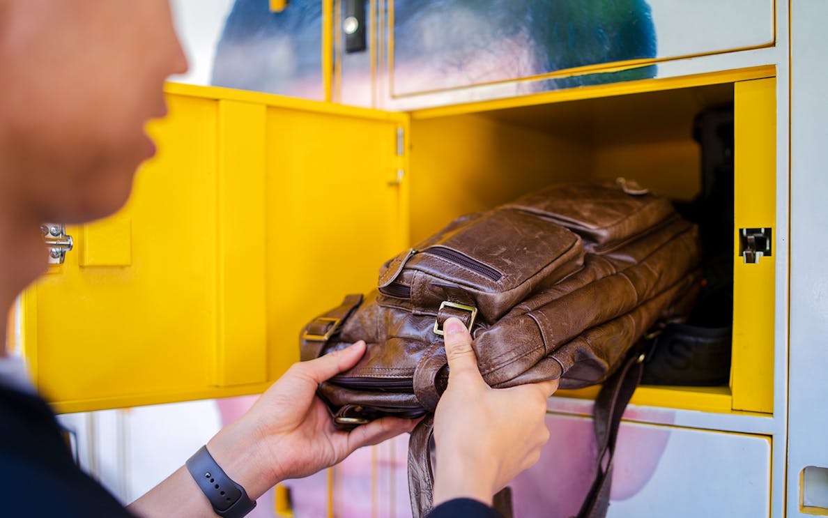 Man placing bag in locker at tourist attraction.