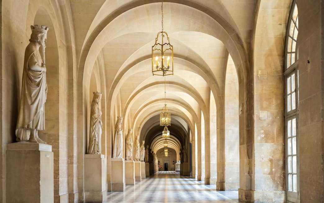 Corridor with statues and arches in Versailles Palace, France.
