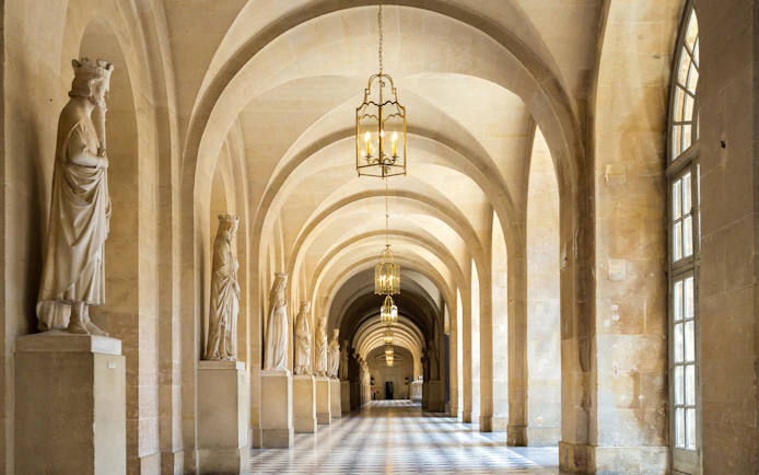 Corridor with statues and arches in Versailles Palace, France.