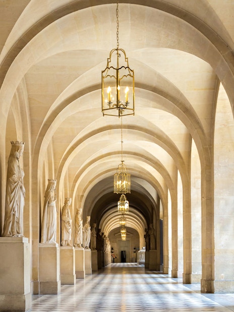 Corridor with statues and arches in Versailles Palace, France.