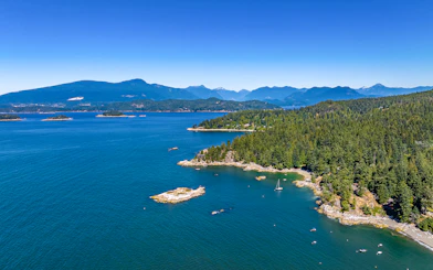 Bowen Island aerial view with forested coastline and sailboat during Vancouver seaplane tour.