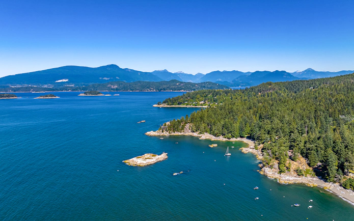 Bowen Island aerial view with forested coastline and sailboat during Vancouver seaplane tour.