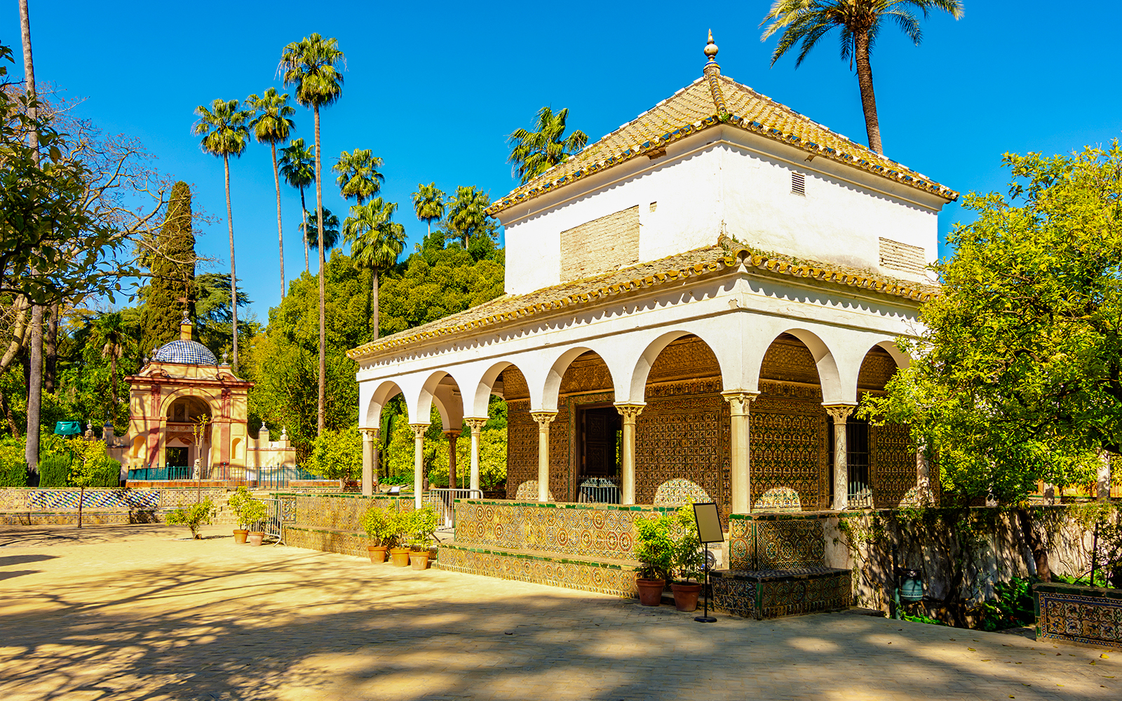 Pavilion in Seville Alcazar gardens with arches and tilework, Spain.