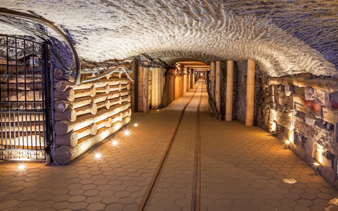 Wieliczka Salt Mine tunnel with wooden supports and illuminated pathway in Poland.