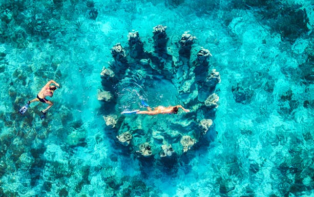 Snorkelers exploring coral formations in clear waters, Northern Coast Gili Islands.