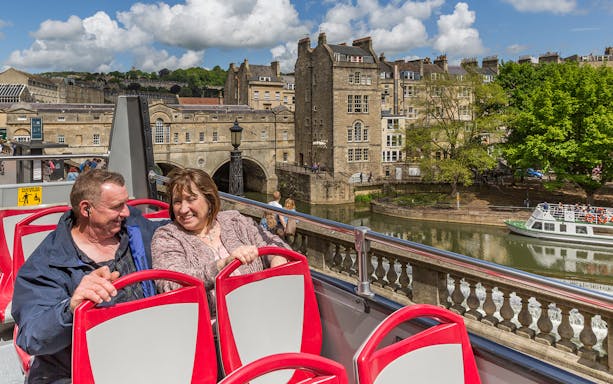 Couple enjoying Bath Hop-On Hop-Off Tour with view of Pulteney Bridge and River Avon.