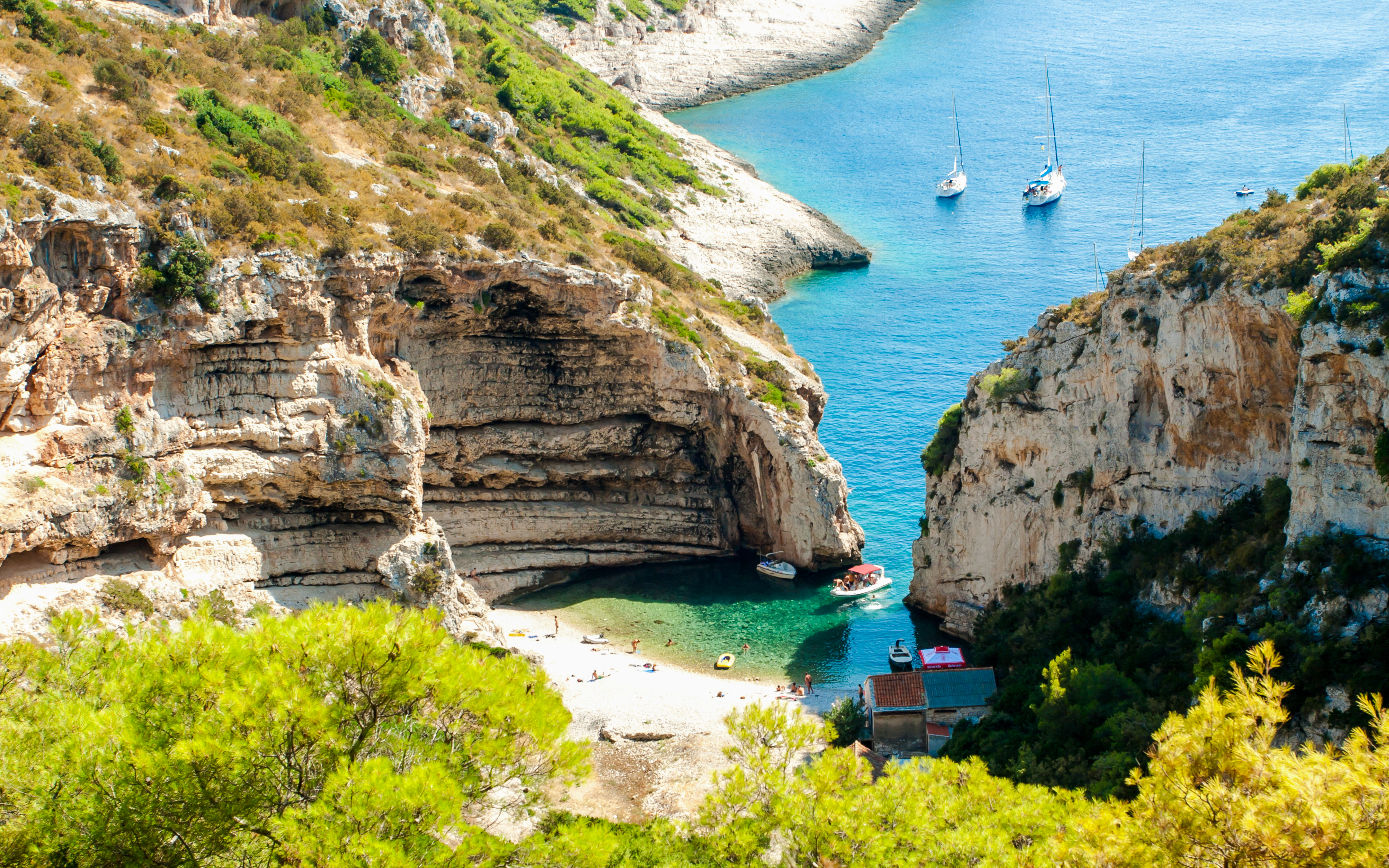 Stiniva Bay on Vis Island with boats and beach surrounded by cliffs.