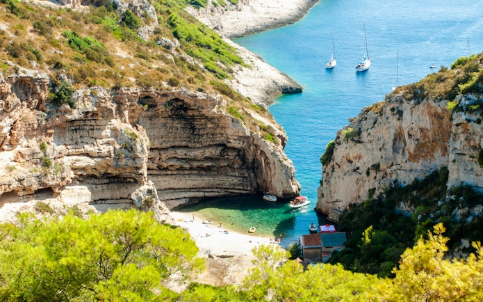 Stiniva Bay on Vis Island with boats and beach surrounded by cliffs.