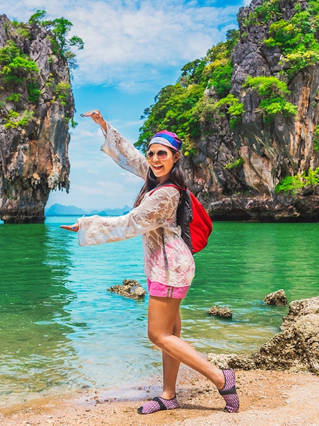 Woman posing at James Bond Island, Thailand, with limestone cliffs and turquoise water in the background.