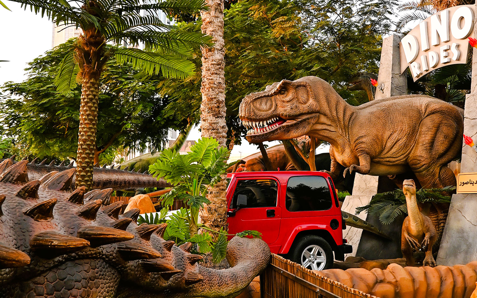Dinosaur sculptures and red jeep at Dino Rides, Dubai Garden Glow.