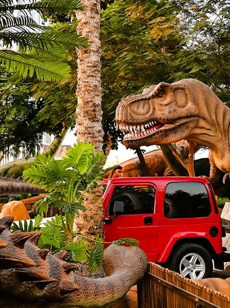 Dinosaur sculptures and red jeep at Dino Rides, Dubai Garden Glow.