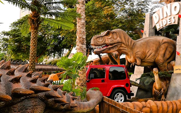 Dinosaur sculptures and red jeep at Dino Rides, Dubai Garden Glow.