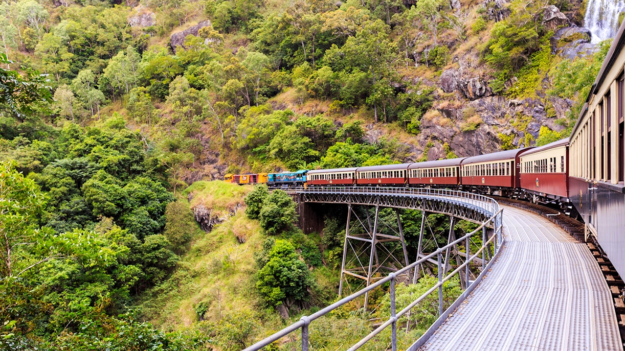 Kuranda Scenic Railway crossing a bridge through lush rainforest in Cairns, Australia.