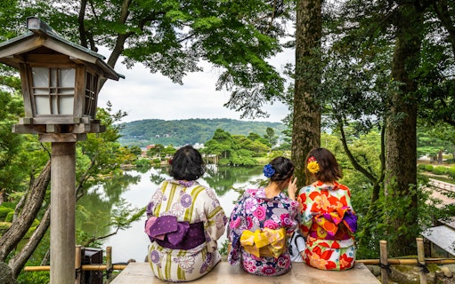 Women in kimonos sitting on a bench overlooking Kenrokuen Garden, Kanazawa, Japan.