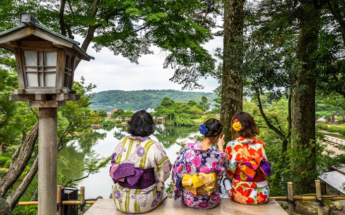 Women in kimonos sitting on a bench overlooking Kenrokuen Garden, Kanazawa, Japan.