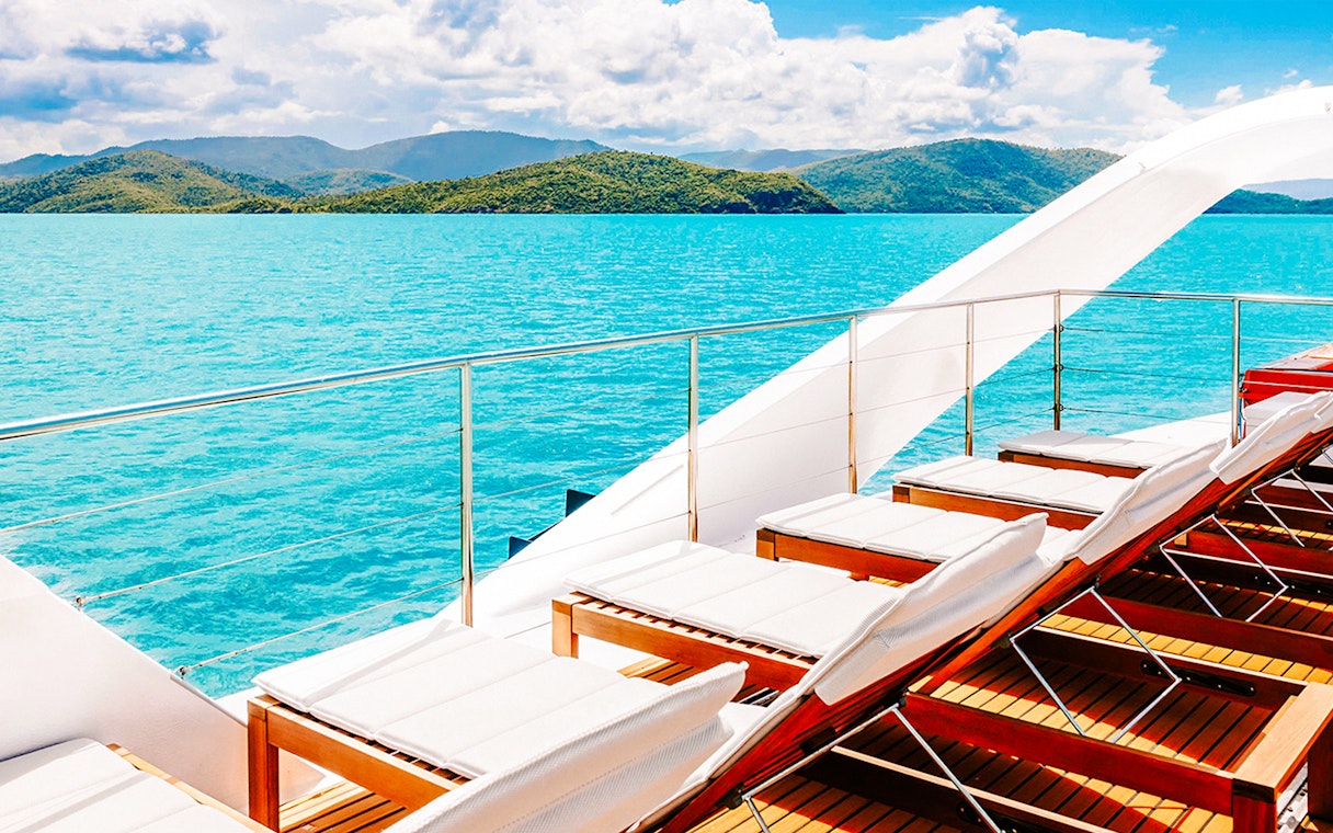 Sun loungers on a boat deck overlooking turquoise waters and islands on the ZigZag Whitsundays Day Tour.