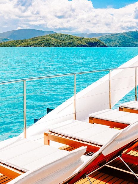 Sun loungers on a boat deck overlooking turquoise waters and islands on the ZigZag Whitsundays Day Tour.