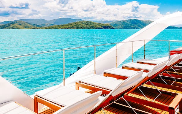 Sun loungers on a boat deck overlooking turquoise waters and islands on the ZigZag Whitsundays Day Tour.