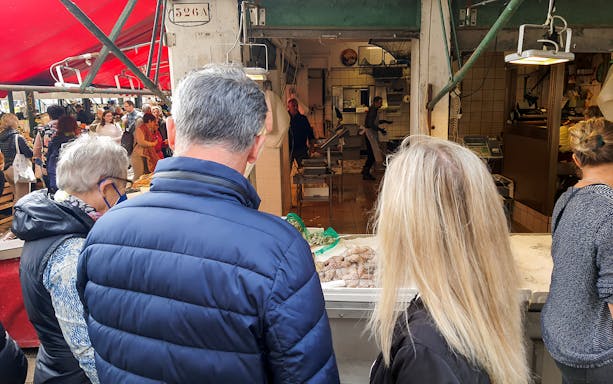 Visitors exploring a bustling seafood market in Venice during a guided culinary tour.