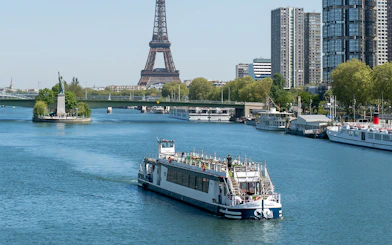 Cruise boat on the Seine River with Eiffel Tower and Paris skyline in the background.