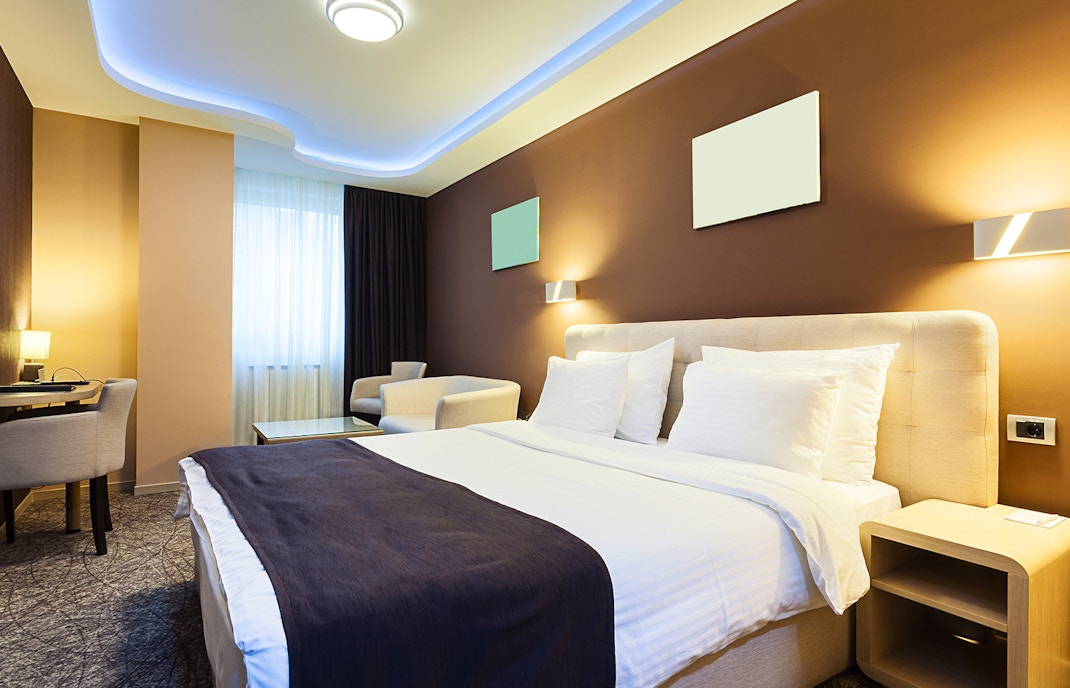 hotel room with bed, chairs, and window.