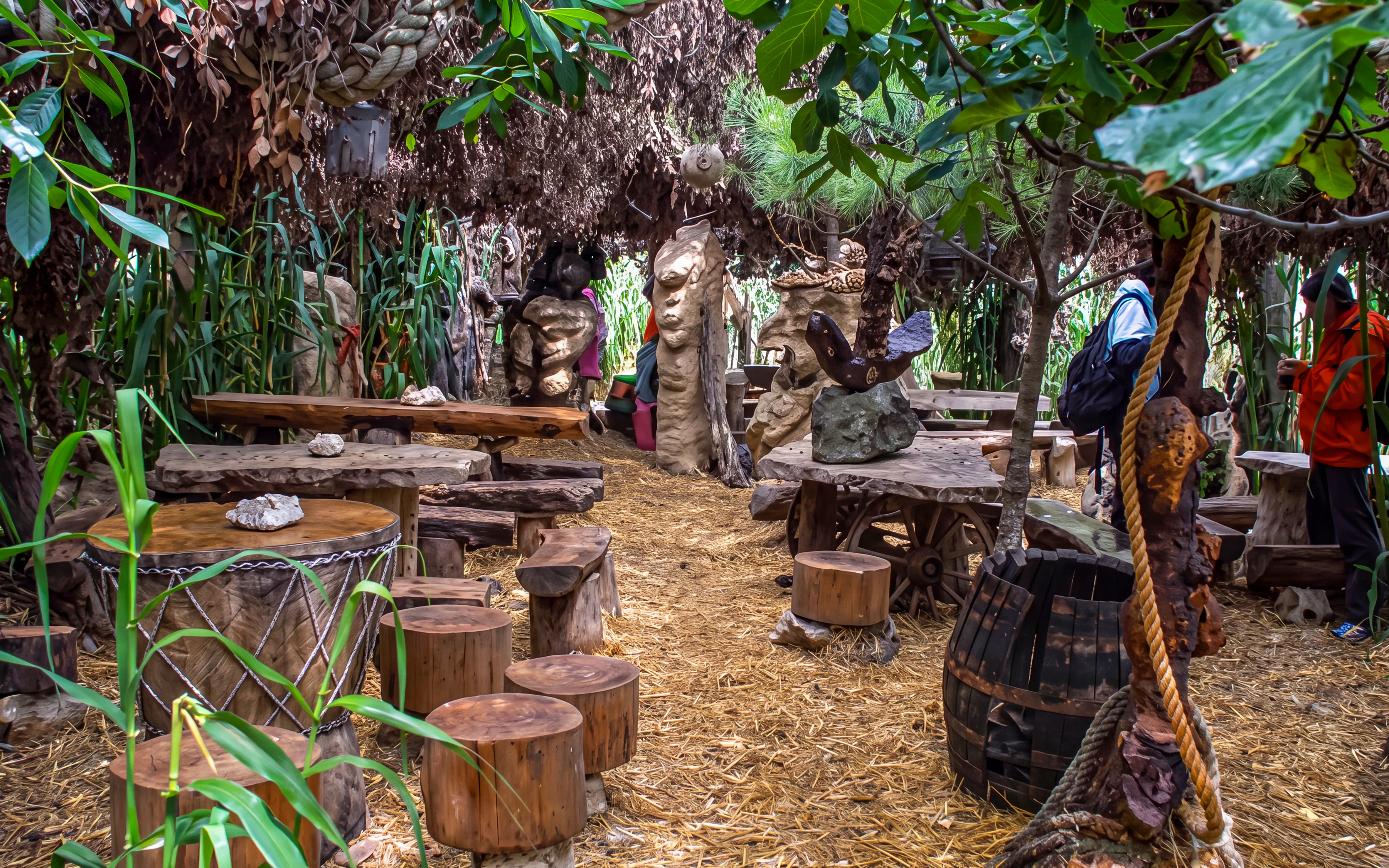 Rustic outdoor seating area with wooden tables and stools surrounded by lush greenery in Cape Kamenjak.