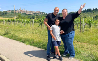 Family enjoying a vineyard with San Gimignano in the background during a Tuscan food and wine tour.