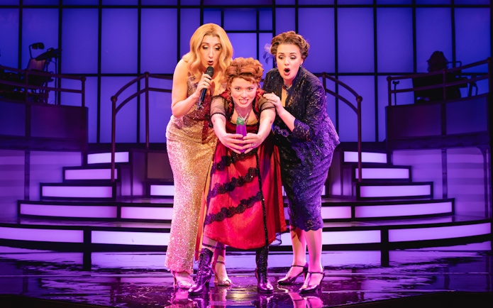 Stage performance of Titanique Westend with three actors on a vibrant set.