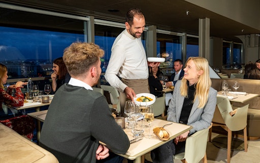 Server presenting dinner to a couple at Madame Brasserie, Eiffel Tower, Paris.