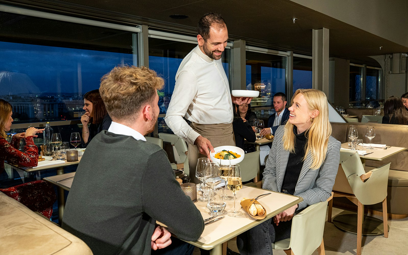 Waitier serving food to the couple at Madame Brasserie Eiffel Tower Restaurant, Paris