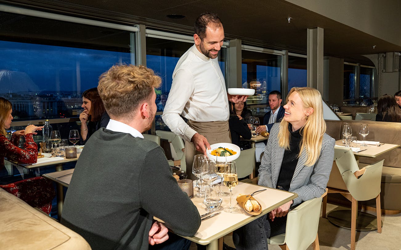 Server presenting dinner to a couple at Madame Brasserie, Eiffel Tower, Paris.