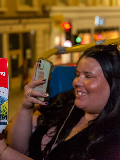 Sightseeing bus tour brochure held by a person on a night tour in London.