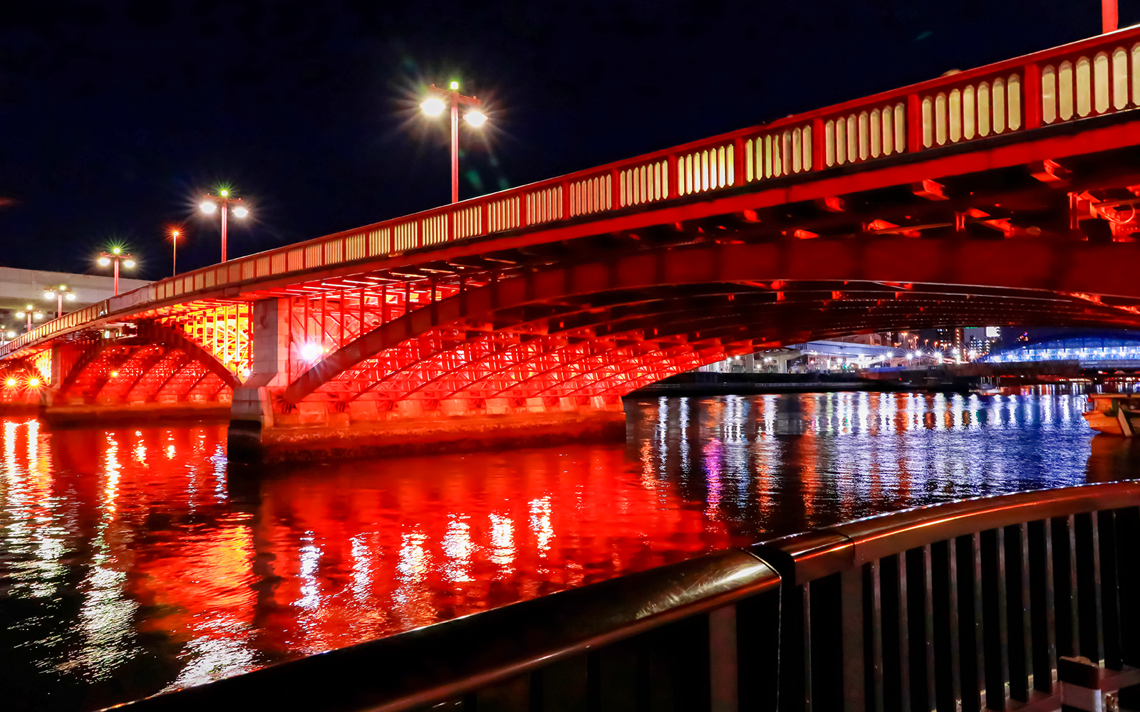 Azuma Bridge illuminated at night, reflecting on the Sumida River in Tokyo.