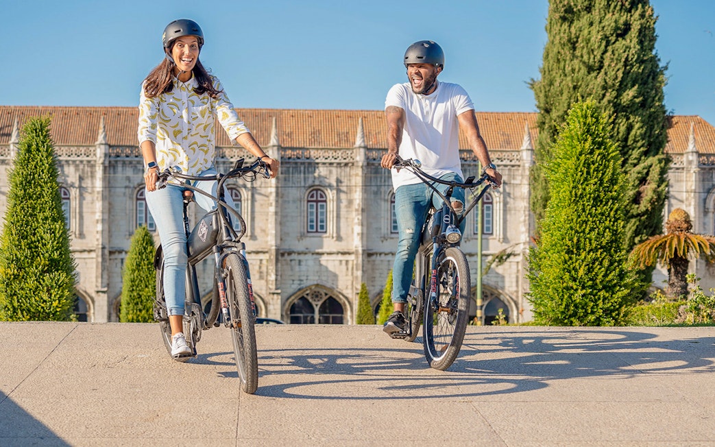 Cyclists enjoying Lisbon e-bike tour near historic Belém landmark.